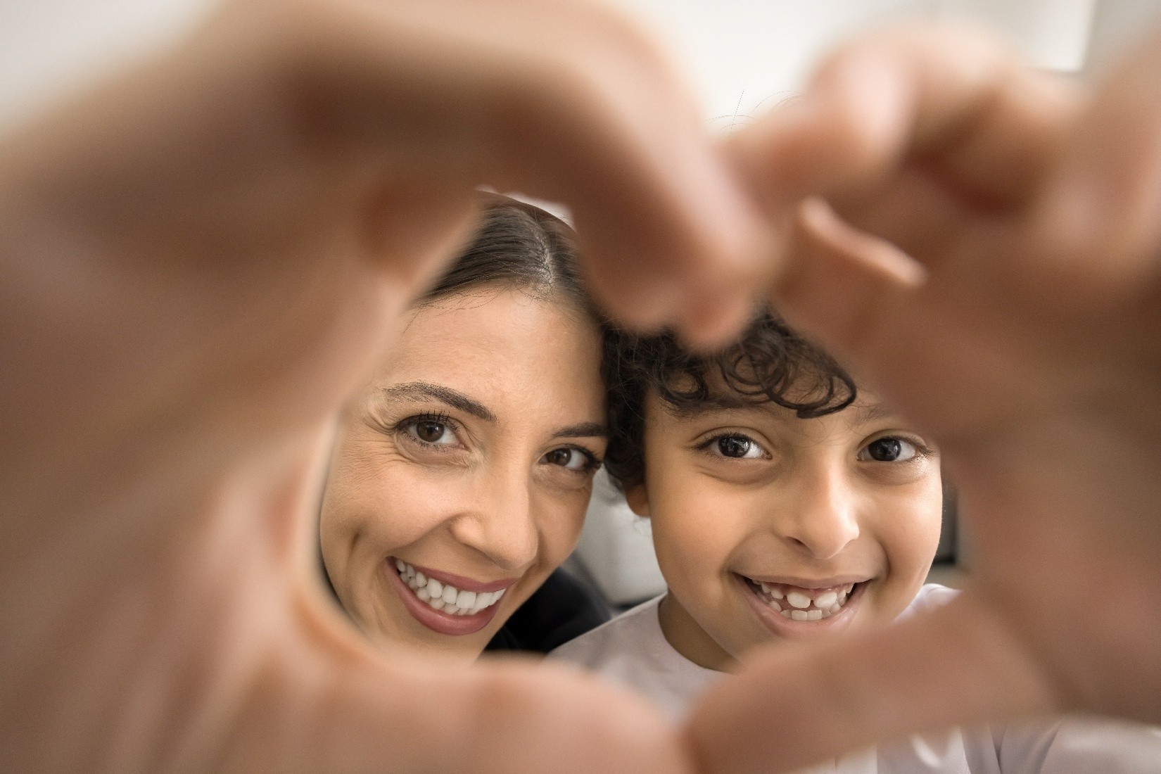 A woman and a little boy holding their hands together to form a heart.