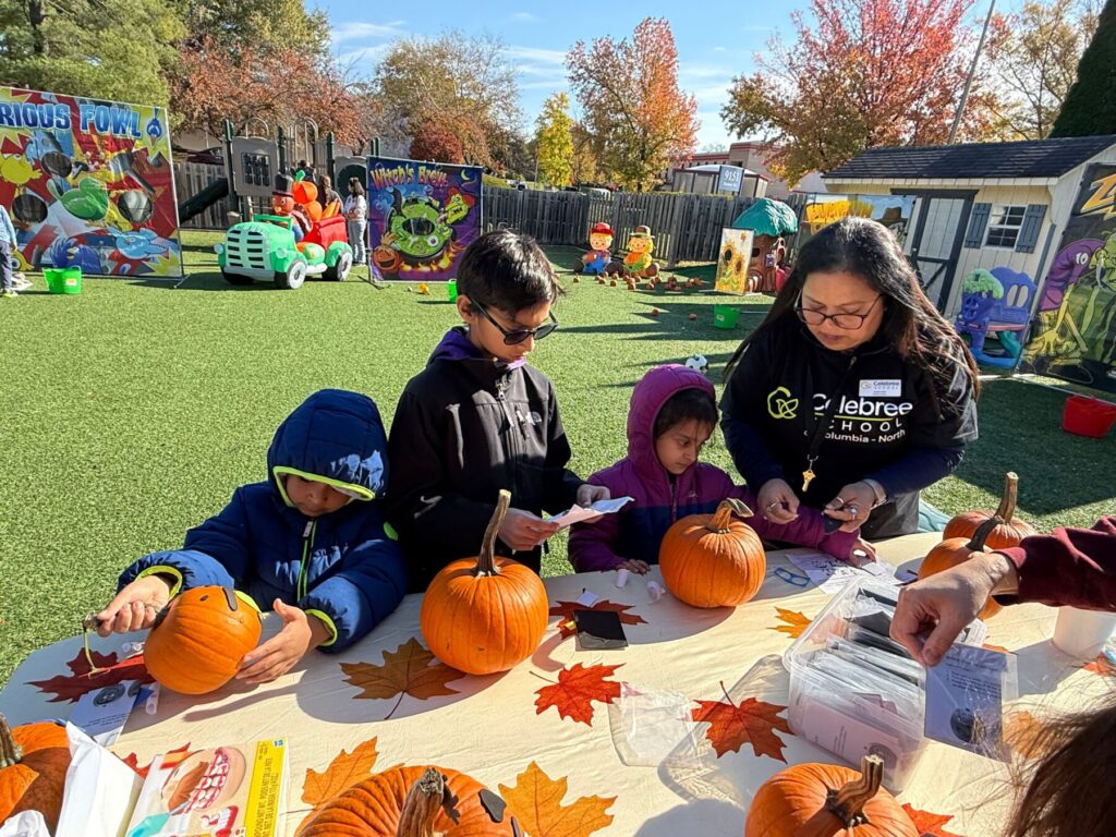 Children decorating pumpkins with teacher