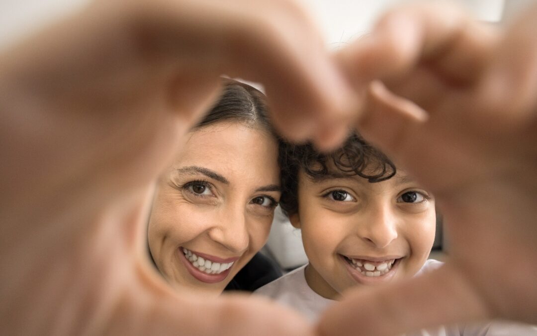 A woman and a little boy holding their hands together to form a heart.