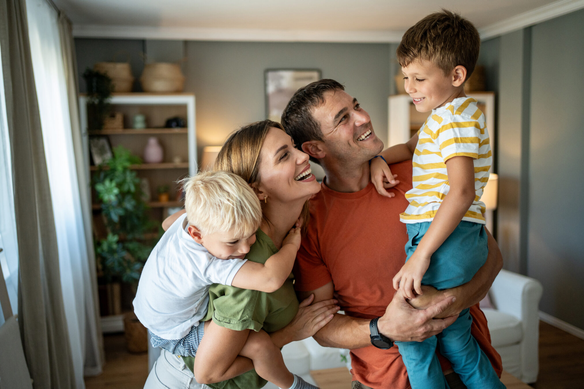 Happy family spending quality time together at home, with parents and young children sharing smiles, hugs, and meaningful moments that support strong family connections and child development.