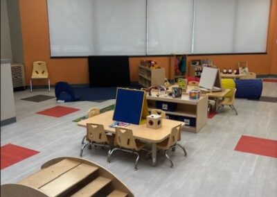 An engaging toddler classroom with small tables, toys and inviting play spaces.