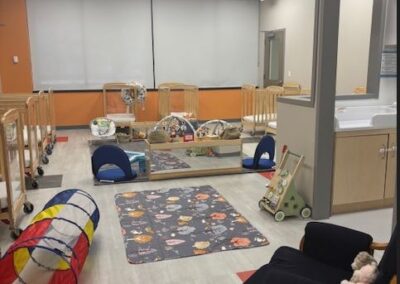 An image of a infant classroom with toys, cribs and engaging play spaces for our little learners.
