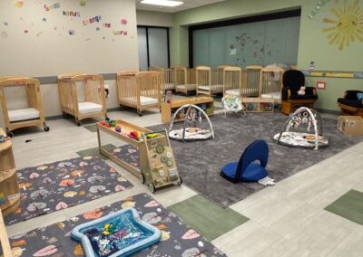 Spacious Celebree classroom with cribs, play mats, and toys.