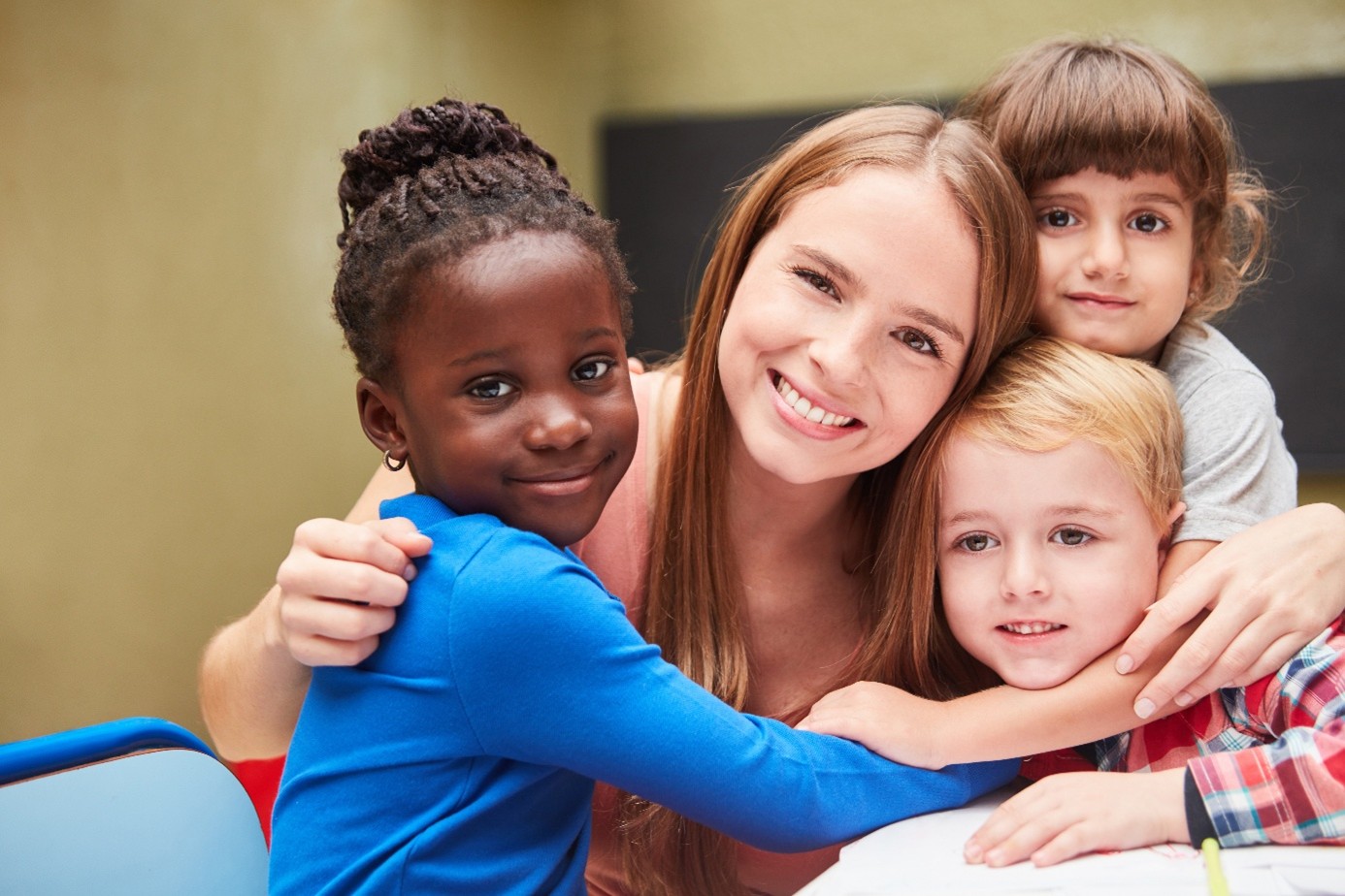 Child Care Smiling teacher hugs three children.
