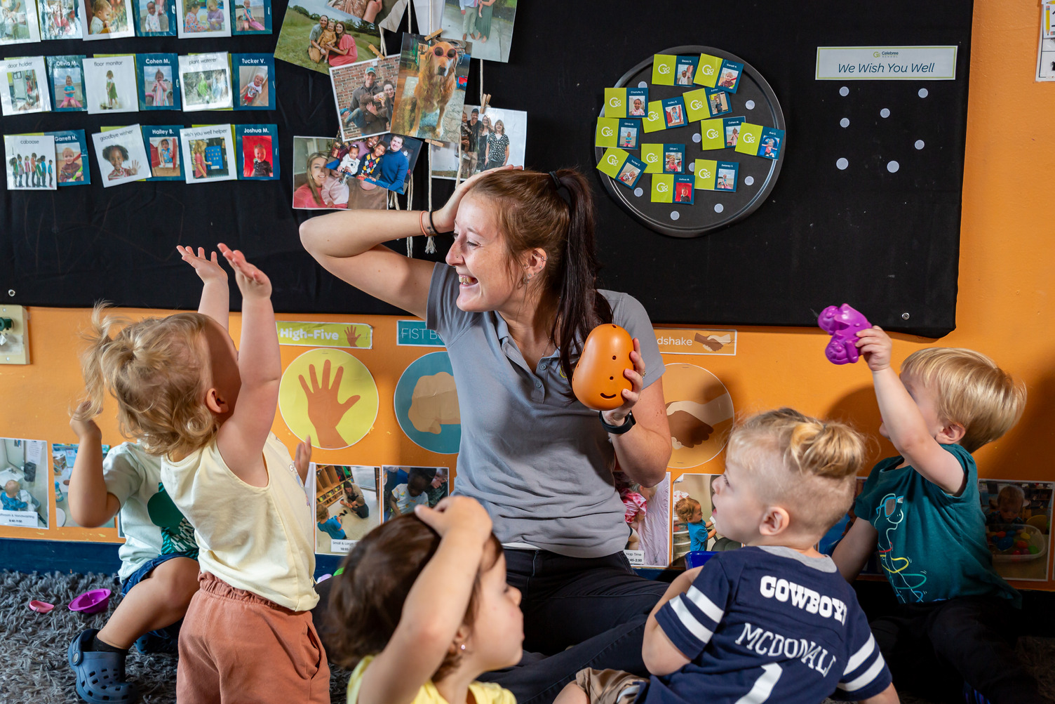Three little girls with blonde hair smiling and holding their artwork at Celebree School preschool. 