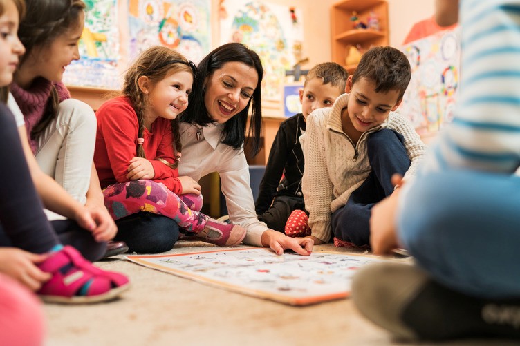 Pre-K students during circle time smiling while the teacher reads a book. 
