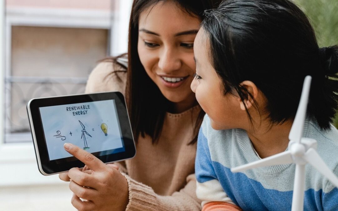 A woman pointing to a tablet that is showing an educational video about renewable energy to a child.