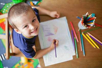 A boy drawing on a paper during preschool in Nottingham.