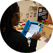 A caregiver at Celebree School looking at a tablet to update a progress report for a parent to view.