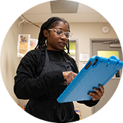 A caregiver at Celebree School looking at a tablet with a blue case to update a daily report for a parent.